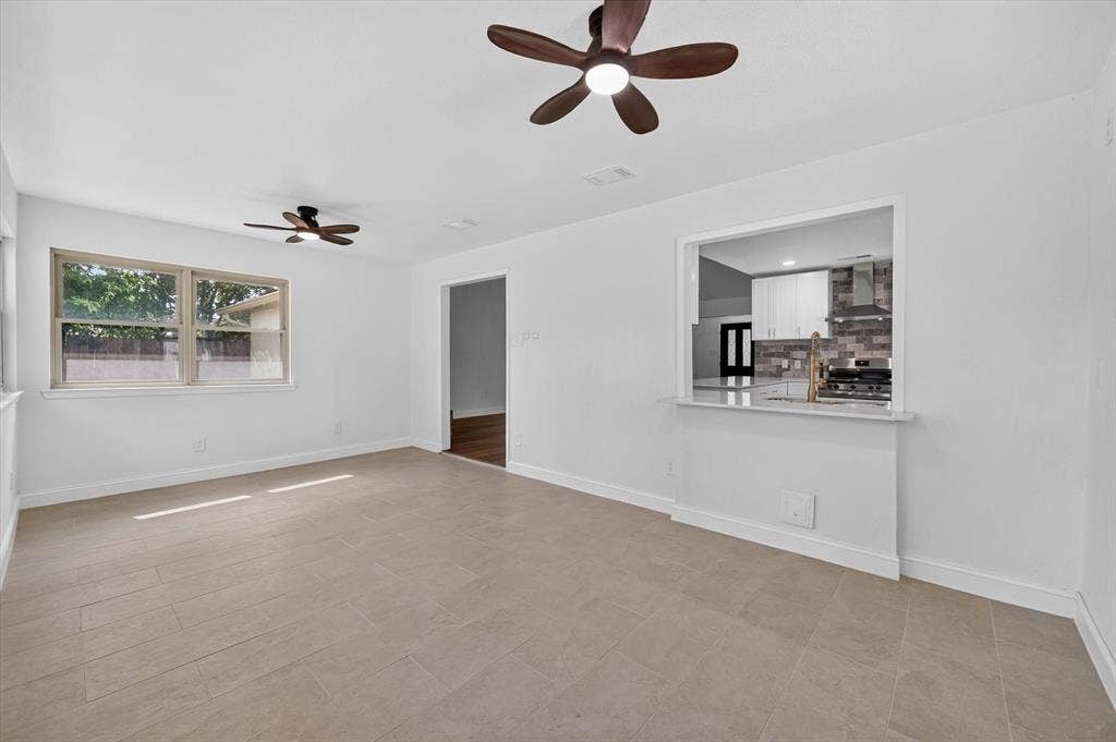 3420 Denbury Drive, Fort Worth, TX 76133 Bright living space featuring large format tile flooring, white painted walls, and two ceiling fans