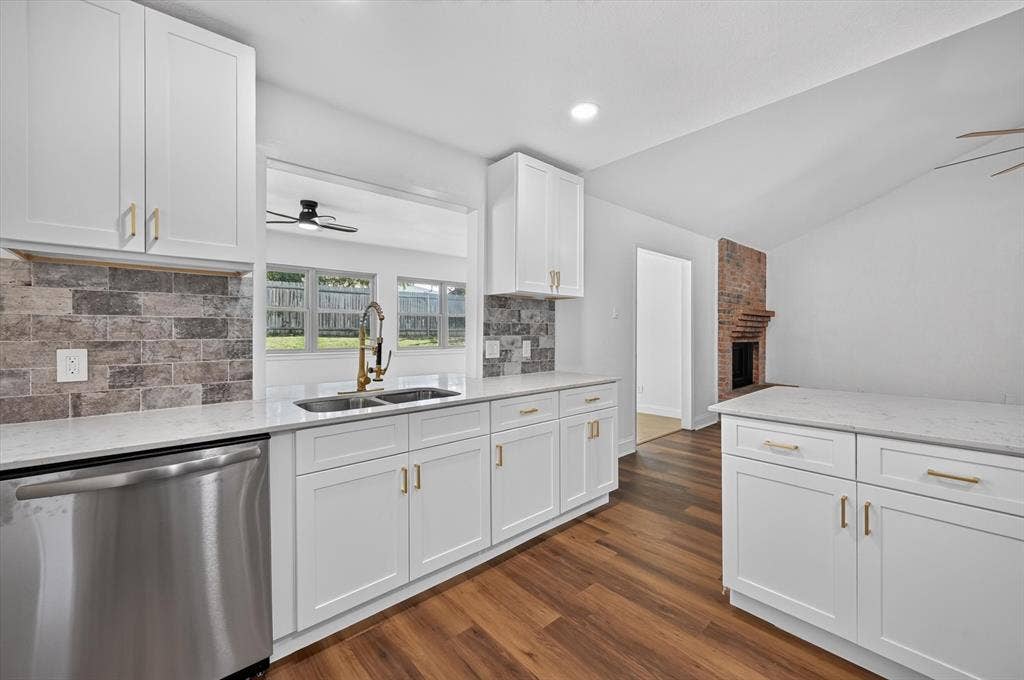 3420 Denbury Drive, Fort Worth, TX 76133 Kitchen featuring white shaker cabinetry with gold-tone hardware, a stainless steel dishwasher, a gold-tone gooseneck faucet, a double basin sink, and wood-finish flooring