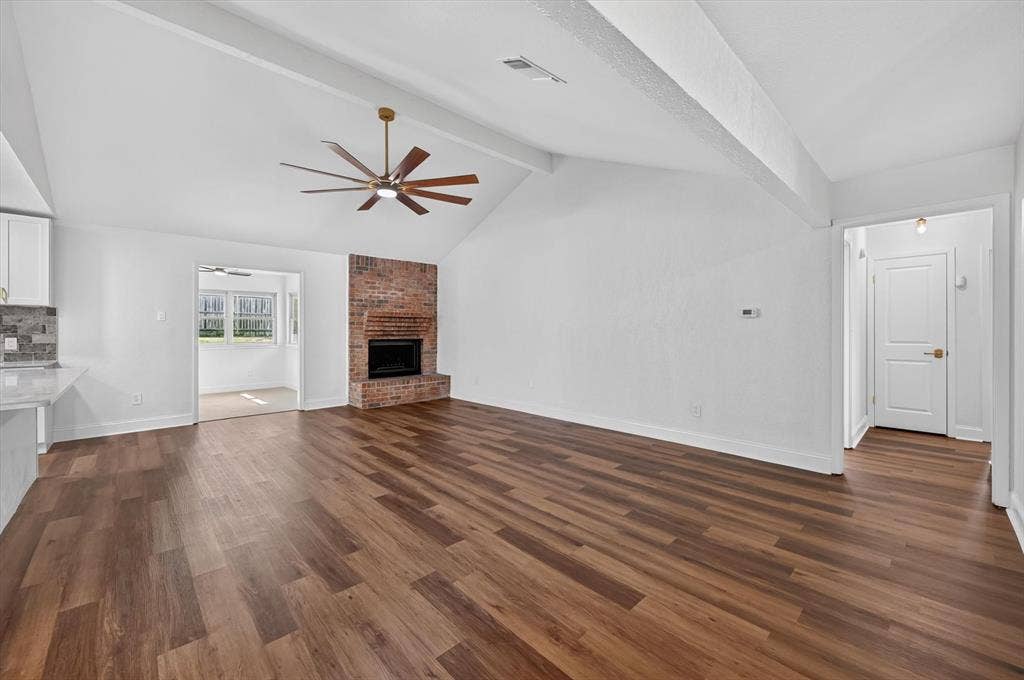 3420 Denbury Drive, Fort Worth, TX 76133 Spacious living area featuring vaulted ceilings, a brick-surround fireplace, wood-finish flooring, and a contemporary ceiling fan