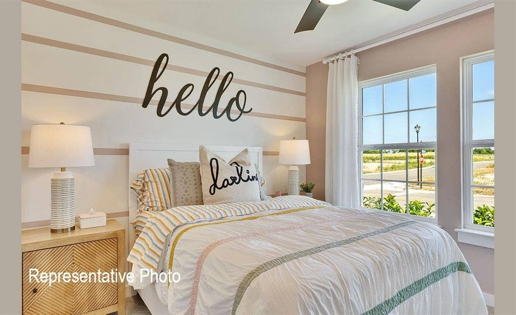 1579 Gentle Night Drive, Forney, TX 75126 Bedroom featuring two large single-hung windows with exterior grid patterns, a ceiling fan, and a light-toned wood-finish nightstand