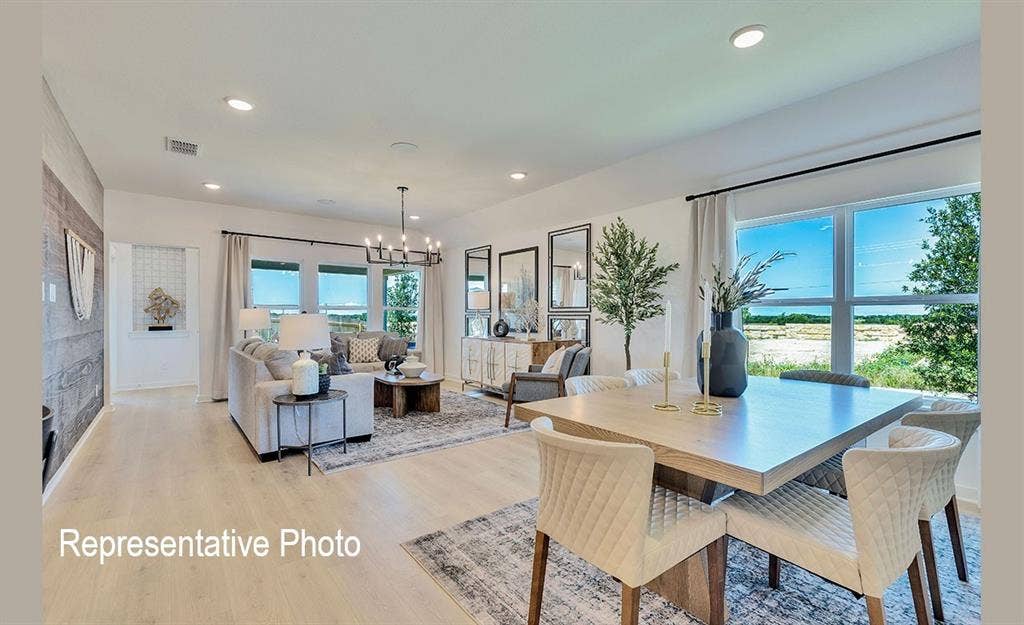 1579 Gentle Night Drive, Forney, TX 75126 Open-concept living and dining areas featuring wood-finish flooring, recessed lighting, a multi-pane window, and a chandelier light fixture