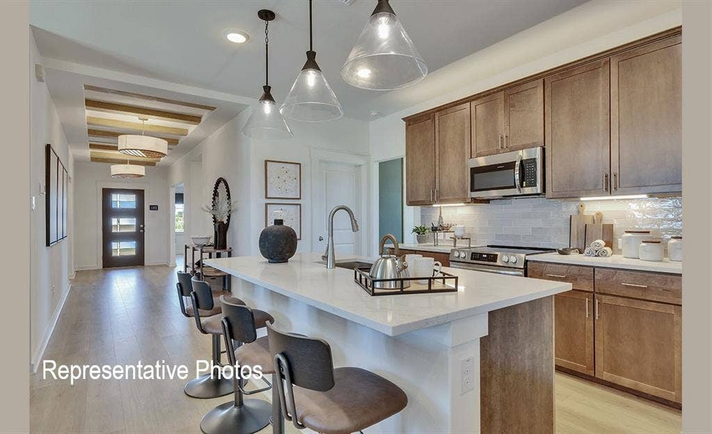 1579 Gentle Night Drive, Forney, TX 75126 Contemporary kitchen featuring a large island with seating, stainless steel appliances, wood-finish cabinetry, and a tile backsplash