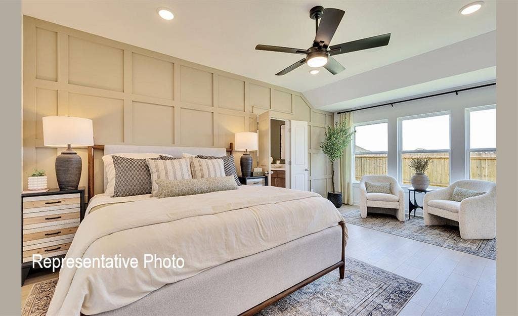 1579 Gentle Night Drive, Forney, TX 75126 Vaulted ceiling bedroom featuring a board and batten accent wall, wood-finish flooring, a ceiling fan with integrated lighting, and multiple windows