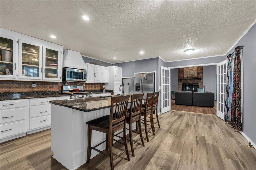 12912 Spring Valley Road, Moody, TX 76557 Bright kitchen featuring white cabinetry, dark stone countertops, stainless steel appliances, and wood-finish flooring