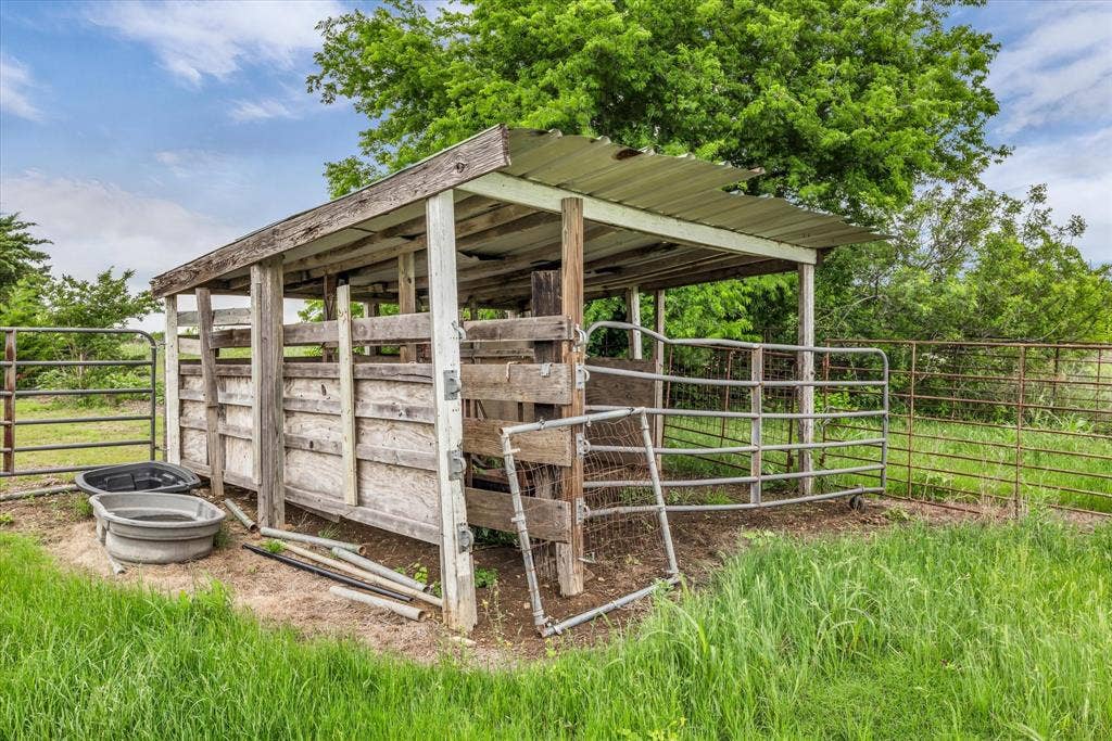 12912 Spring Valley Road, Moody, TX 76557 Sheltered livestock pen featuring a corrugated metal roof, wood framing, and metal gates