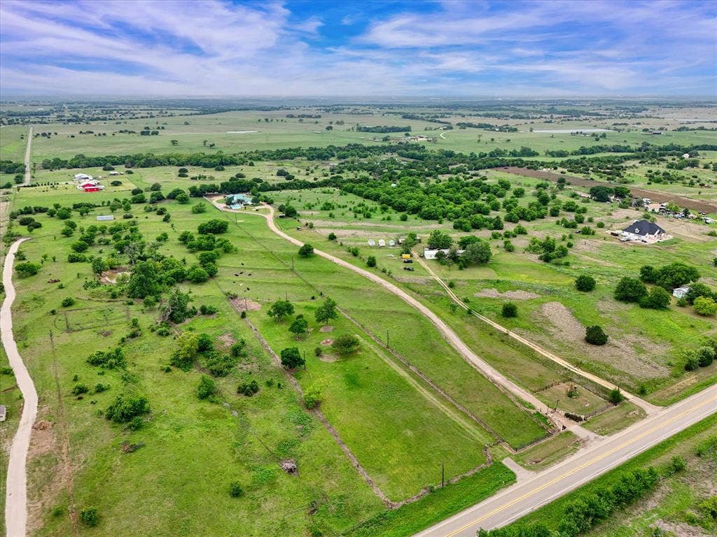 12912 Spring Valley Road, Moody, TX 76557 Expansive rural acreage featuring green pastures, scattered trees, and multiple structures