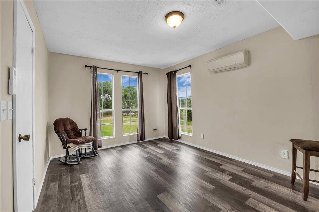 12912 Spring Valley Road, Moody, TX 76557 Interior room featuring dark wood-finish flooring, light neutral-toned walls, and two large windows with dark curtain rods