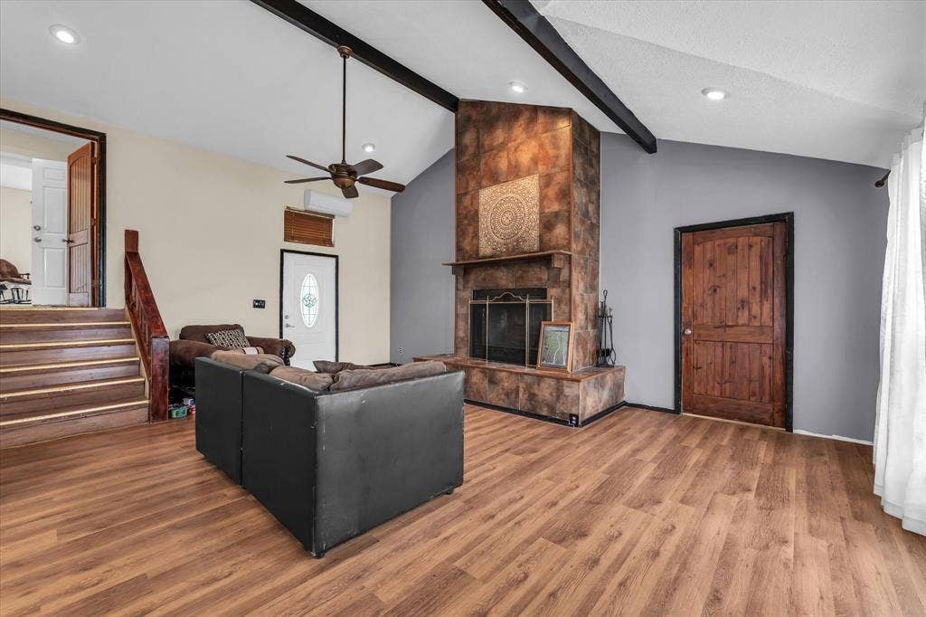 12912 Spring Valley Road, Moody, TX 76557 Vaulted ceiling living space featuring wood-finish flooring, a stone-clad fireplace with hearth, and exposed ceiling beams