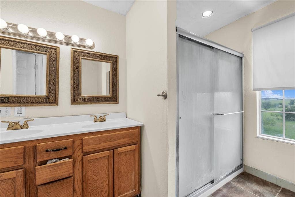 12912 Spring Valley Road, Moody, TX 76557 Bathroom vanity featuring dual sinks, gold-finish faucets, and ornate framed mirrors under a multi-bulb light fixture