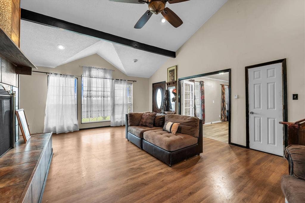 12912 Spring Valley Road, Moody, TX 76557 Spacious living area featuring wood-finish flooring, vaulted ceilings with exposed beams, and a ceiling fan
