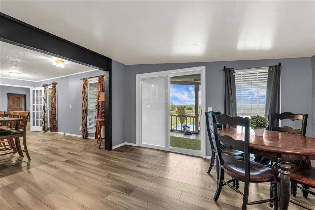 12912 Spring Valley Road, Moody, TX 76557 Spacious interior featuring wood-finish flooring, a sliding glass door to an outdoor deck, and a window with blinds