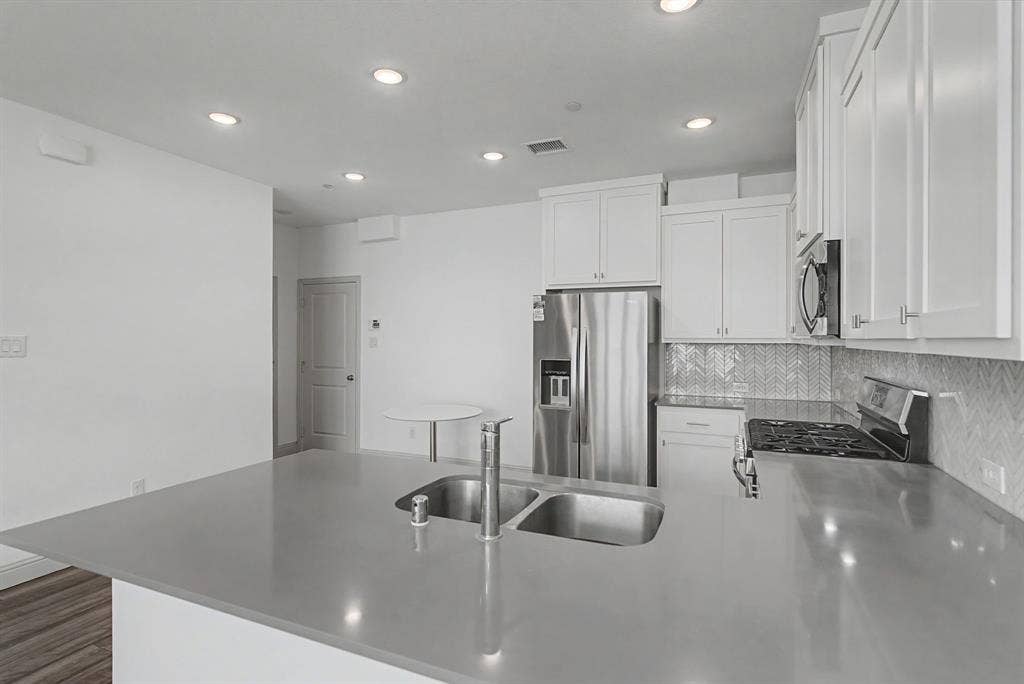 6032 Silverado Trail, McKinney, TX 75070 Kitchen island featuring a double basin stainless steel sink and gooseneck faucet