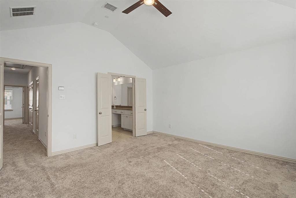 6032 Silverado Trail, McKinney, TX 75070 Spacious room featuring vaulted ceilings, light carpeting, and a ceiling fan