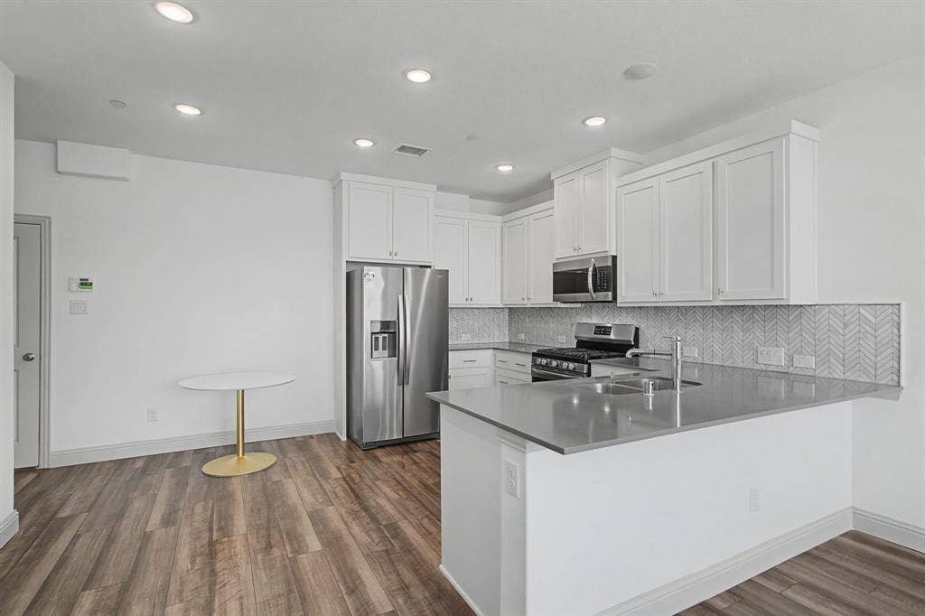 6032 Silverado Trail, McKinney, TX 75070 Modern kitchen featuring white cabinetry, stainless steel appliances, and a grey countertop
