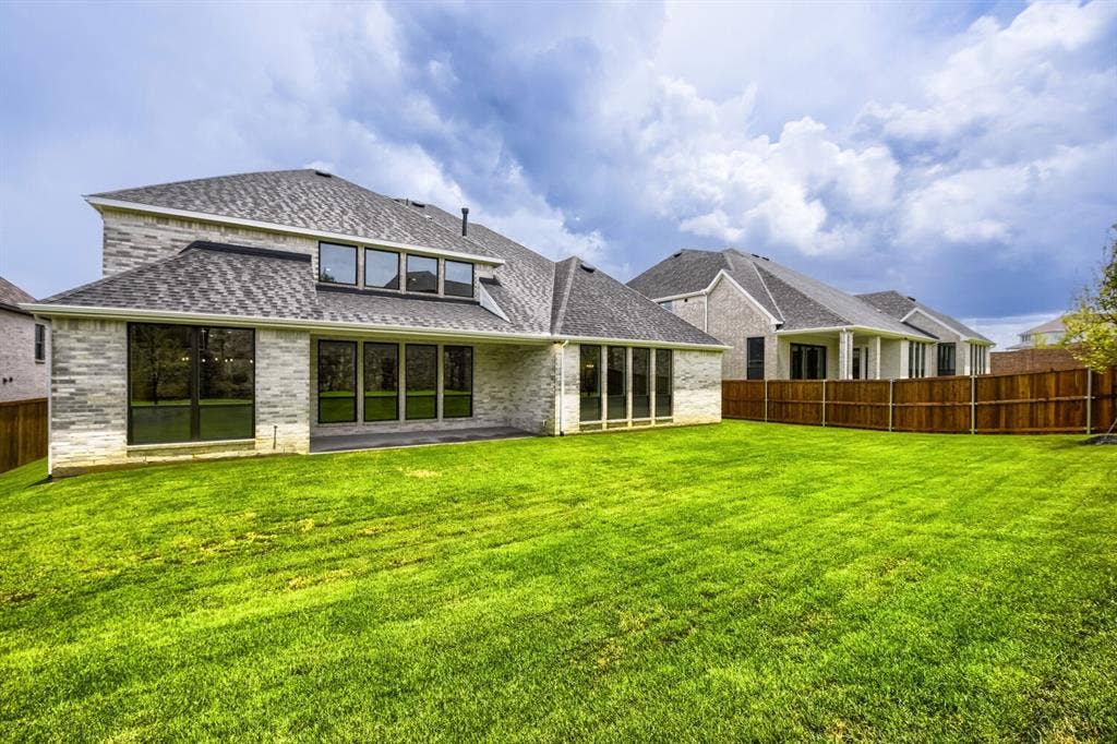Expansive backyard featuring a manicured lawn, full privacy fencing, and a covered patio area