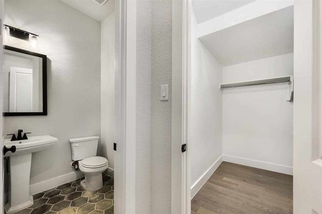 Powder room featuring a pedestal sink with matte black fixtures, a rectangular mirror with a black frame, and hexagonal floor tile