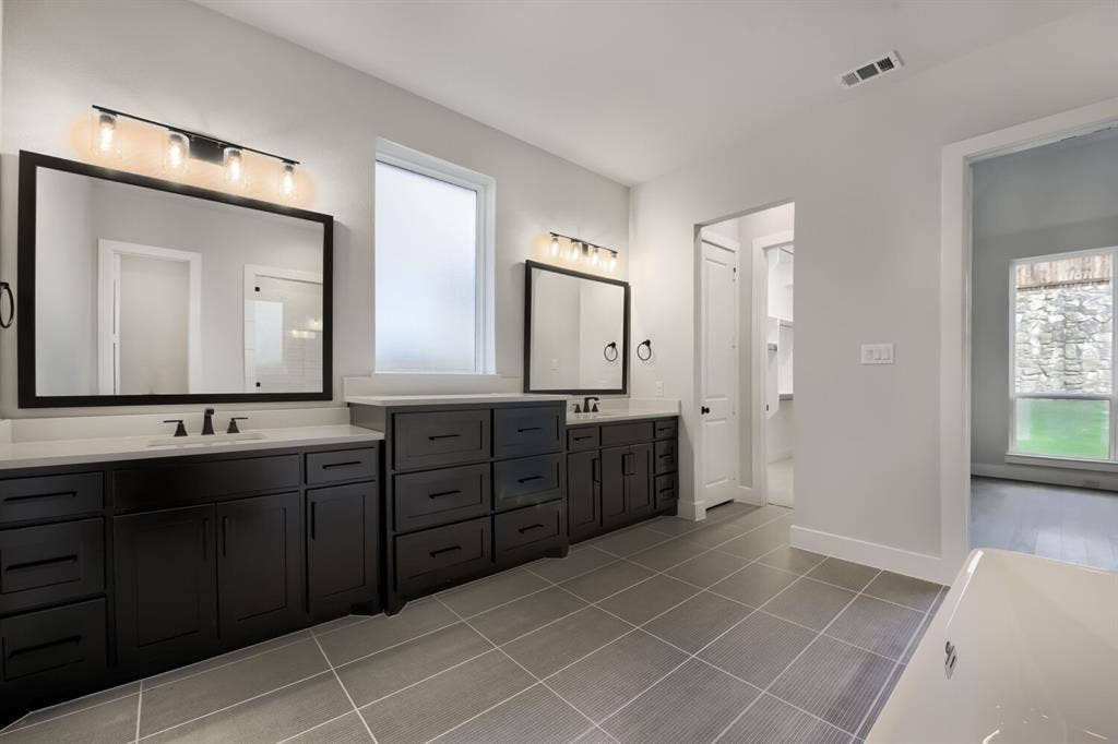 Spacious bathroom featuring dual dark wood vanities with white countertops, integrated sinks, and matte black fixtures