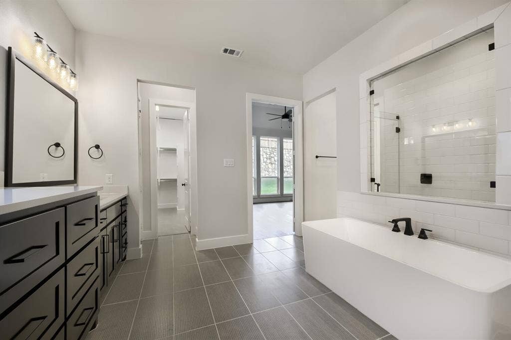 Contemporary bathroom featuring a freestanding soaking tub with matte black fixtures, a glass-enclosed shower, and subway tile surround