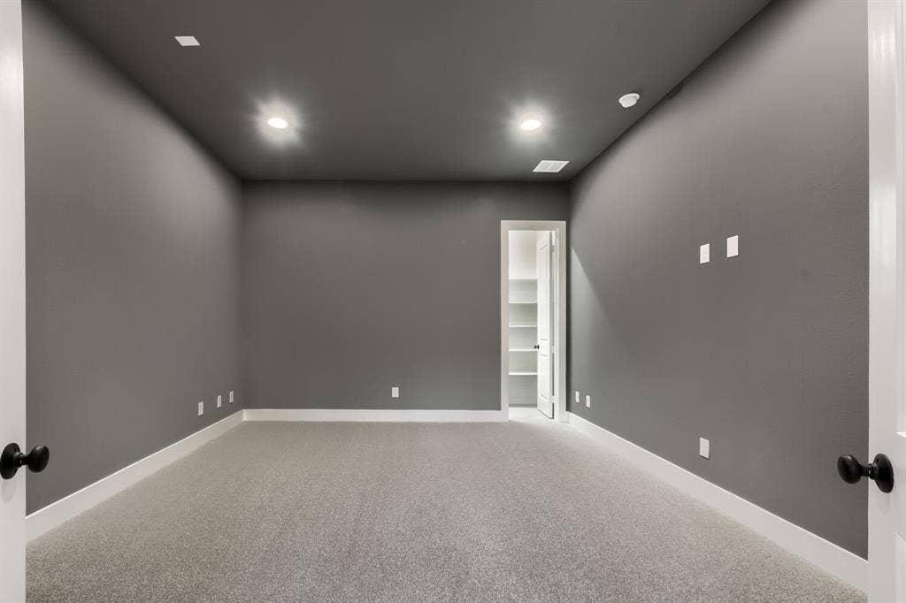 Carpeted room featuring recessed lighting, a built-in closet with shelving, dark gray walls, white baseboards, and matte black door hardware