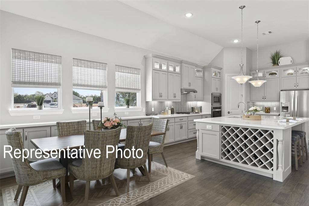 4384 Laurel Trail, Midlothian, TX 76065 Spacious open-concept kitchen featuring light-toned cabinetry, stainless steel appliances, a central island with integrated wine storage, and wood-finish flooring