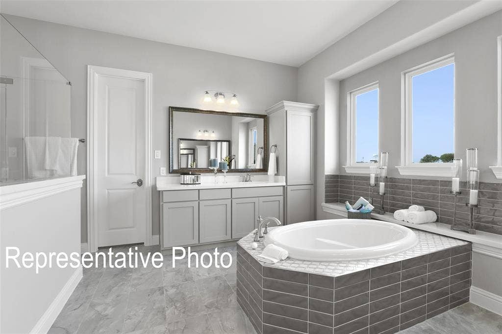 4384 Laurel Trail, Midlothian, TX 76065 Bathroom featuring a built-in soaking tub with gray subway tile surround, double vanity with gray cabinetry and white countertops, large wall-mounted mirror, and a separate glass-enclosed shower