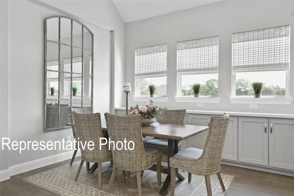 4384 Laurel Trail, Midlothian, TX 76065 Dining area featuring vaulted ceilings, light gray wall color, three windows with natural light, built-in lower cabinetry with a light-colored countertop, and wood-finish flooring