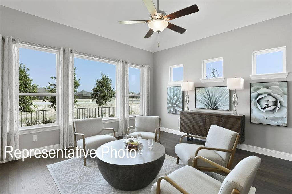 4384 Laurel Trail, Midlothian, TX 76065 Spacious living area featuring expansive windows, wood-finish flooring, a ceiling fan with integrated lighting, and a built-in credenza