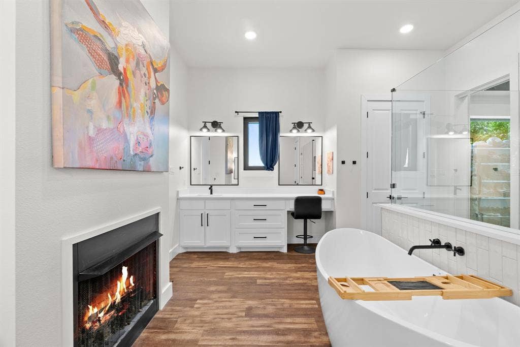 3621 Fritz Lane, Corinth, TX 76208 Freestanding soaking tub with wall-mounted matte black faucet, alongside a dual vanity with white cabinetry and dark hardware