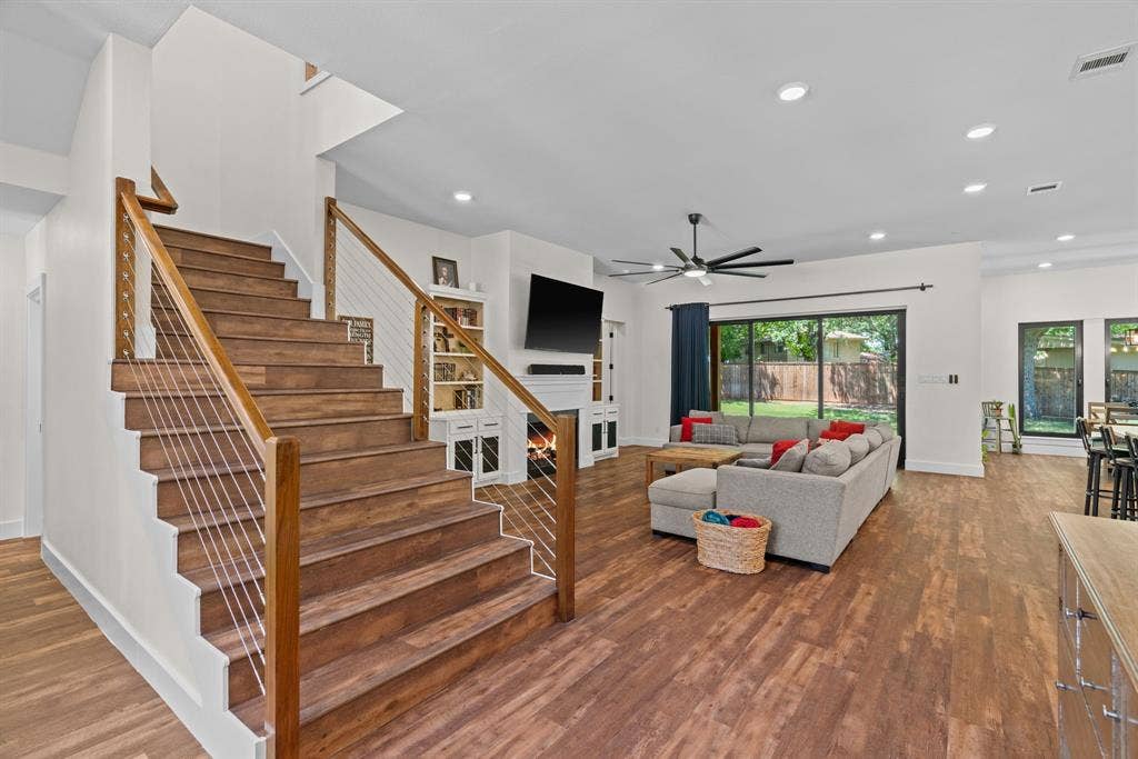 3621 Fritz Lane, Corinth, TX 76208 Wood-finish staircase with cable railing, complemented by wood-finish flooring throughout the open-concept living area