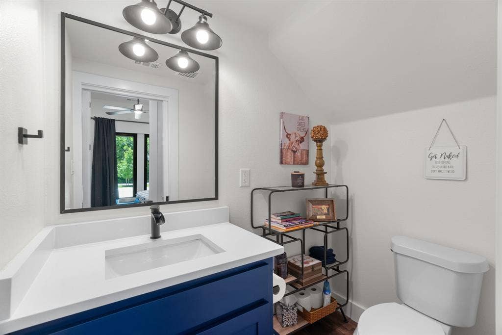 3621 Fritz Lane, Corinth, TX 76208 Bathroom featuring a blue vanity with a white countertop and integrated sink, a dark-framed mirror, and a three-bulb vanity light fixture