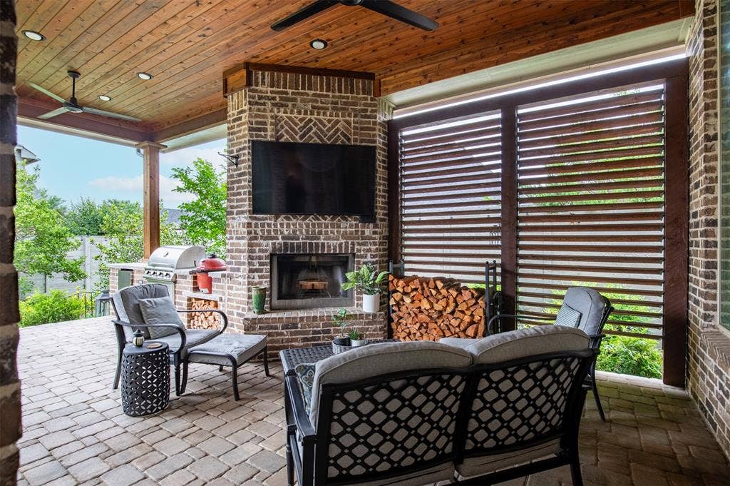1408 9th Street, Argyle, TX 76226 The beautiful outdoor living area features a cozy fireplace and adjustable wooden shutters, offering both comfort and added privacy for year-round enjoyment.