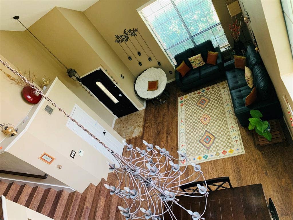 1848 Sonnet Drive, Grapevine, TX 76051 Open-concept living area featuring wood-finish flooring, a large window providing ample natural light, a decorative area rug, and a prominent chandelier
