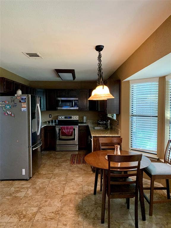 1848 Sonnet Drive, Grapevine, TX 76051 Kitchen featuring stainless steel appliances, dark wood-finish cabinetry, granite countertops, and tiled flooring