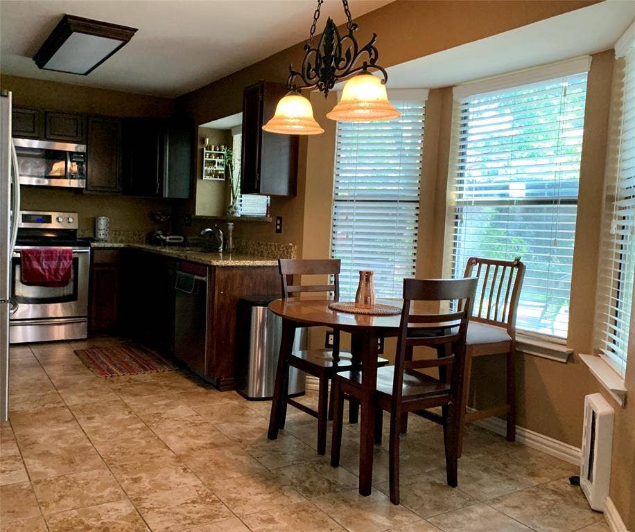 1848 Sonnet Drive, Grapevine, TX 76051 Kitchen featuring stainless steel appliances, dark wood-finish cabinetry, light-toned granite countertops, and tile flooring