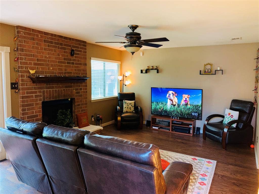 1848 Sonnet Drive, Grapevine, TX 76051 Living room featuring a brick fireplace with a wood mantle, wood-finish flooring, and a ceiling fan with integrated lighting