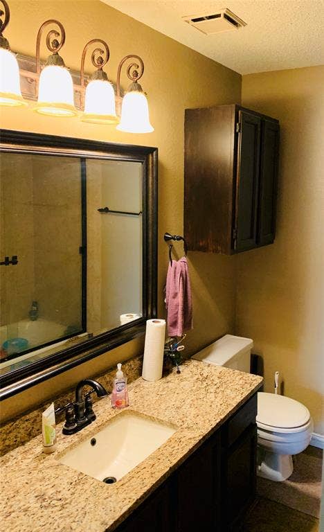 1848 Sonnet Drive, Grapevine, TX 76051 Vanity featuring a stone countertop, built-in sink, and bronze-finish faucet