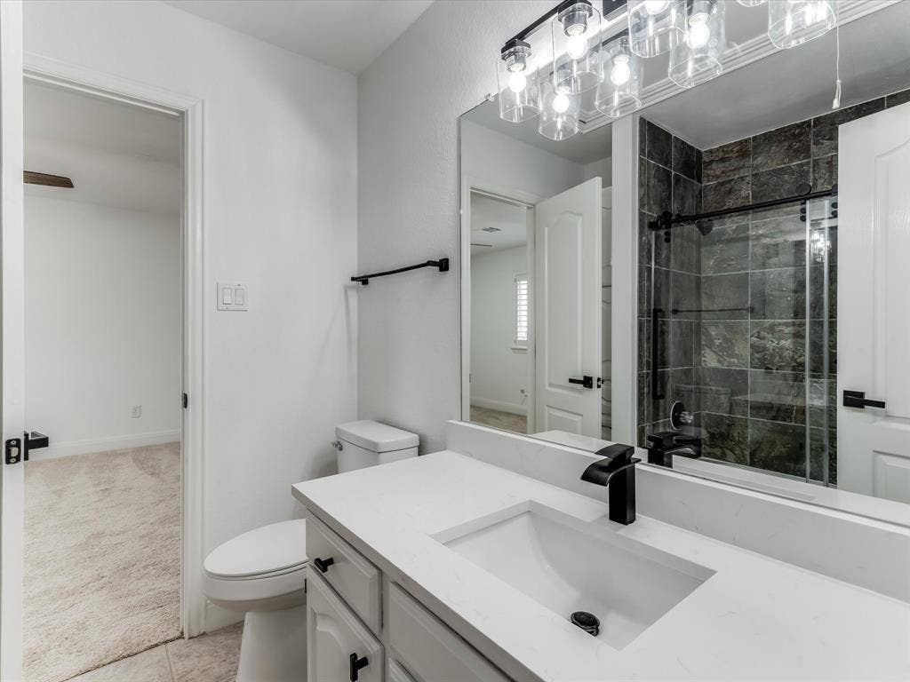 736 Sunkist Lane, Plano, TX 75025 Bathroom featuring a white vanity with a rectangular undermount sink, a matte black faucet, and a large framed mirror