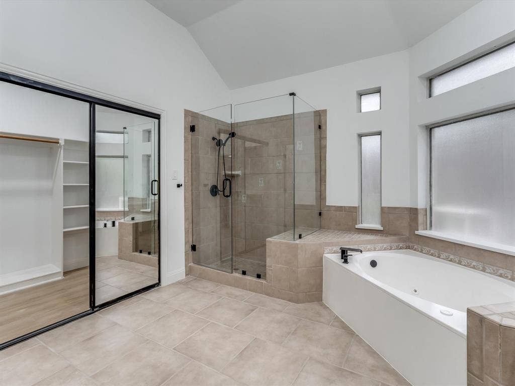 736 Sunkist Lane, Plano, TX 75025 Bathroom featuring a corner soaking tub, a glass-enclosed shower with tiled walls, and light-toned tile flooring