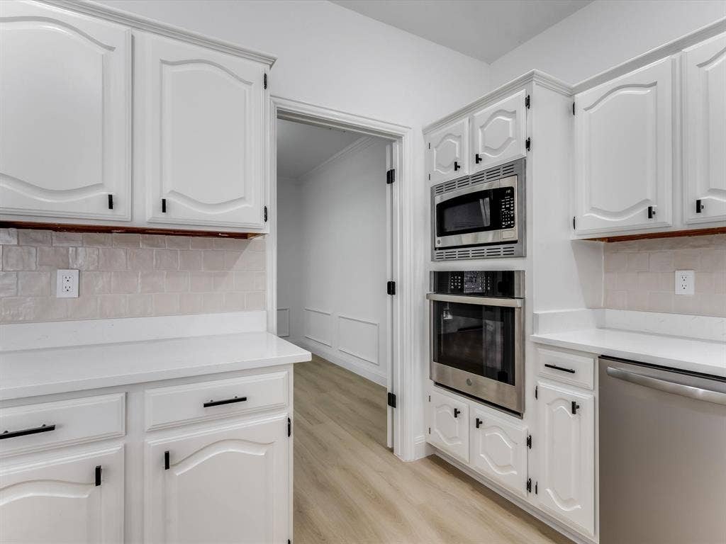 736 Sunkist Lane, Plano, TX 75025 White cabinetry with black hardware, complementing white countertops, and a light-toned tile backsplash