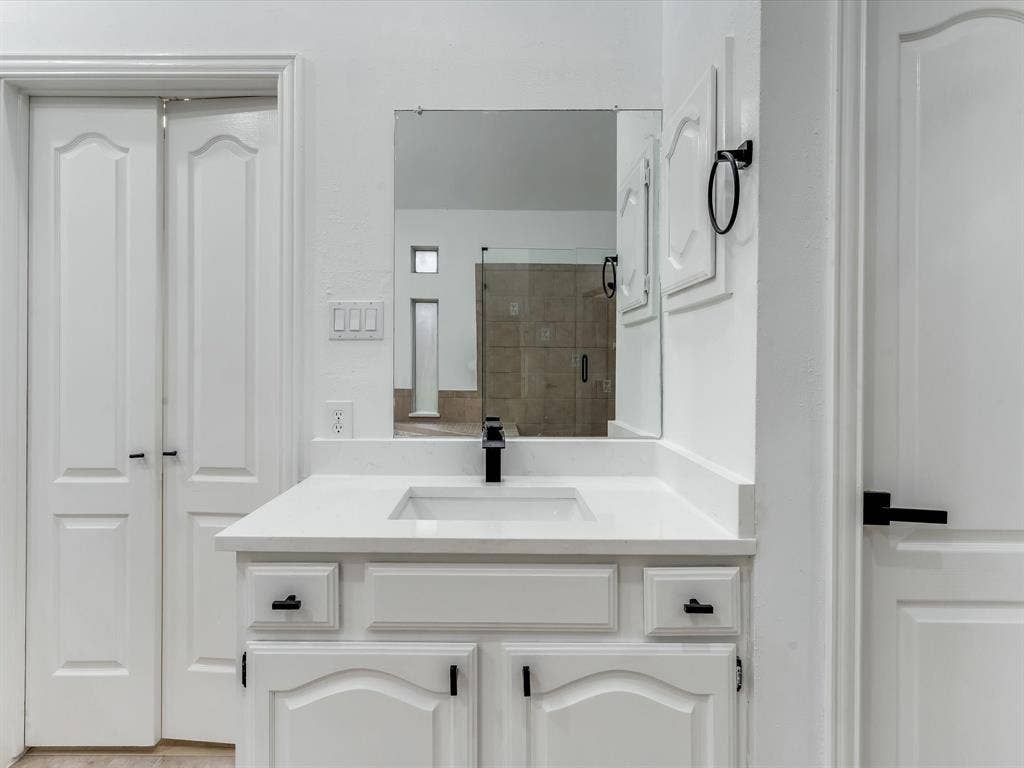 736 Sunkist Lane, Plano, TX 75025 Bathroom vanity featuring a white countertop with an integrated sink, matte black faucet, and white cabinetry