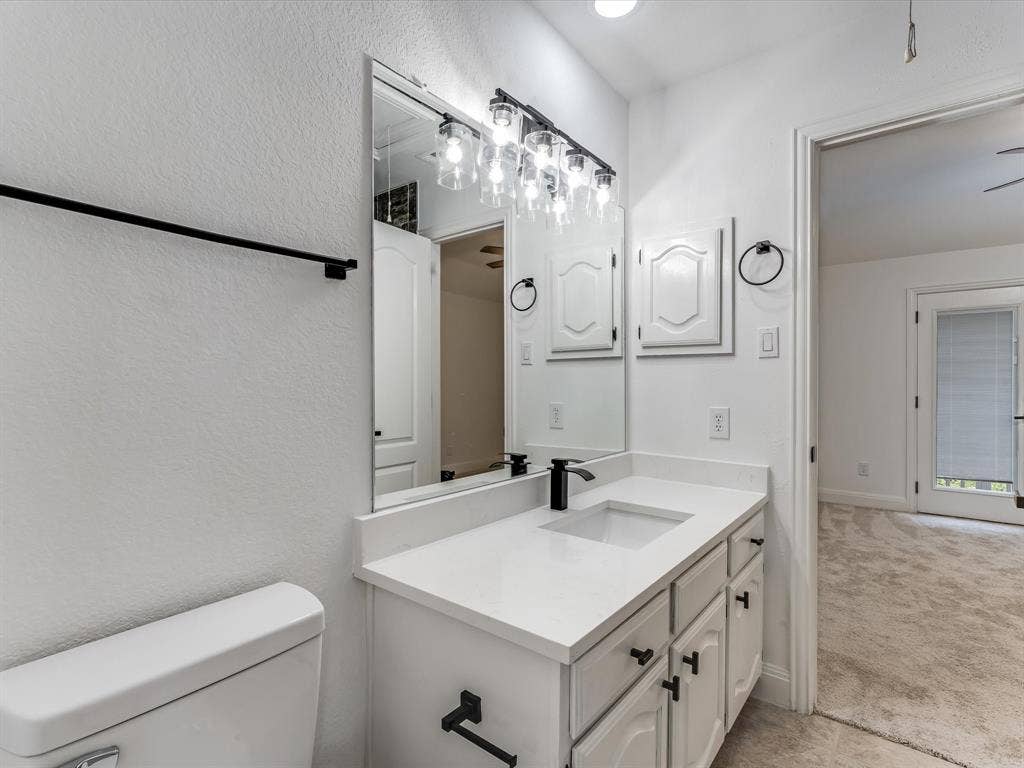 736 Sunkist Lane, Plano, TX 75025 Bathroom vanity featuring a single sink, white countertop, white cabinetry with black hardware, and an overhead light fixture