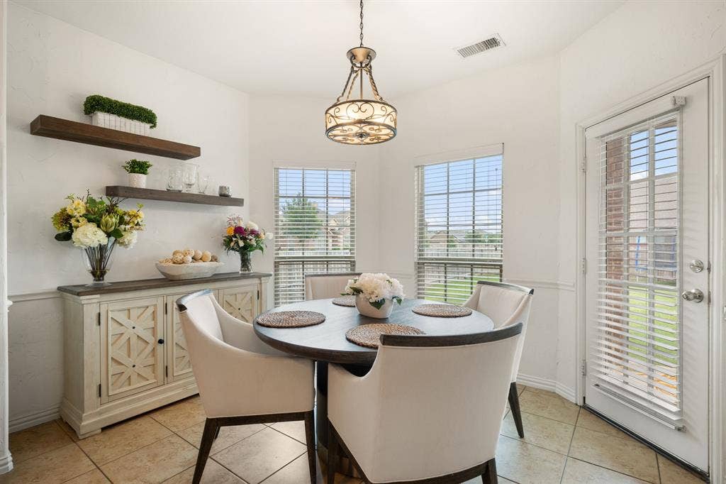 Dining area featuring tile flooring, a decorative chandelier, and natural light from multiple windows and a glass-paneled door