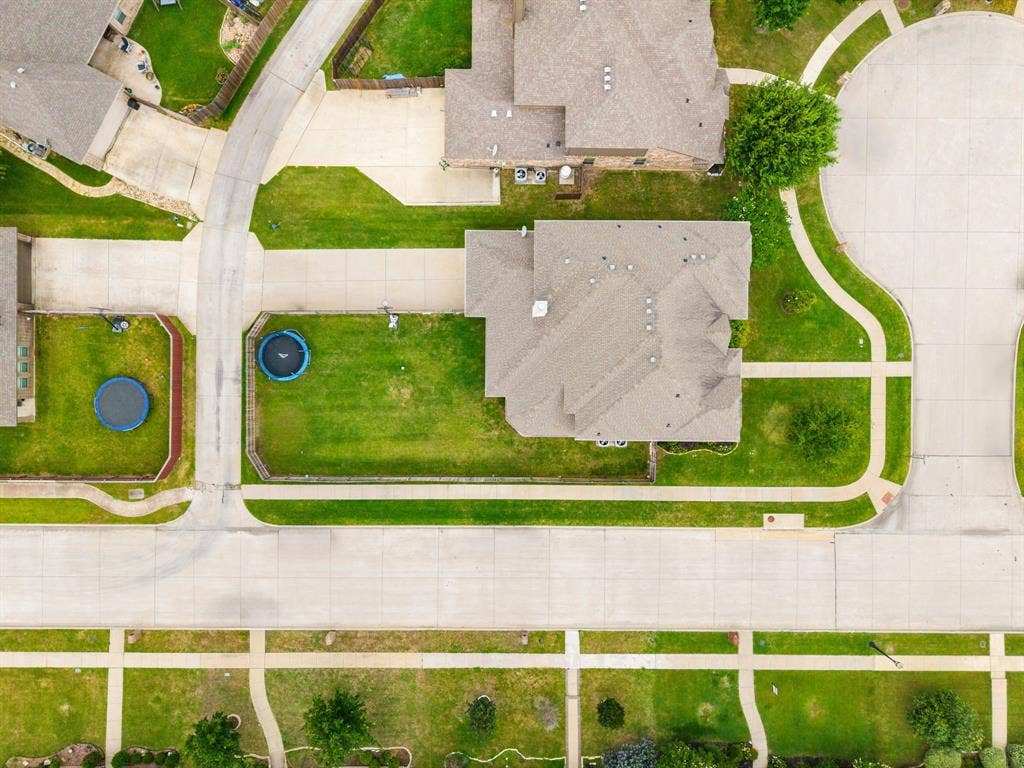 Aerial perspective showcasing a residential corner lot property with a shingle roof and surrounding green lawn