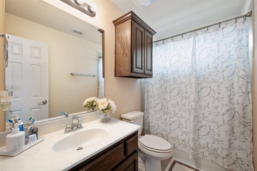 Bathroom featuring a single vanity with an integrated sink, chrome faucet, and a large wall-mounted mirror