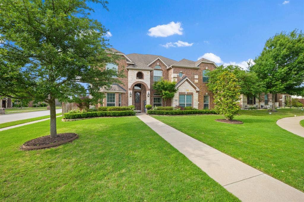 Brick and stone exterior featuring an arched entryway with a solid wood door