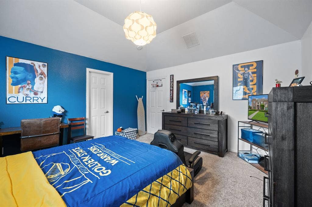 Vaulted ceiling bedroom featuring carpeting, a white paneled door, and a modern light fixture