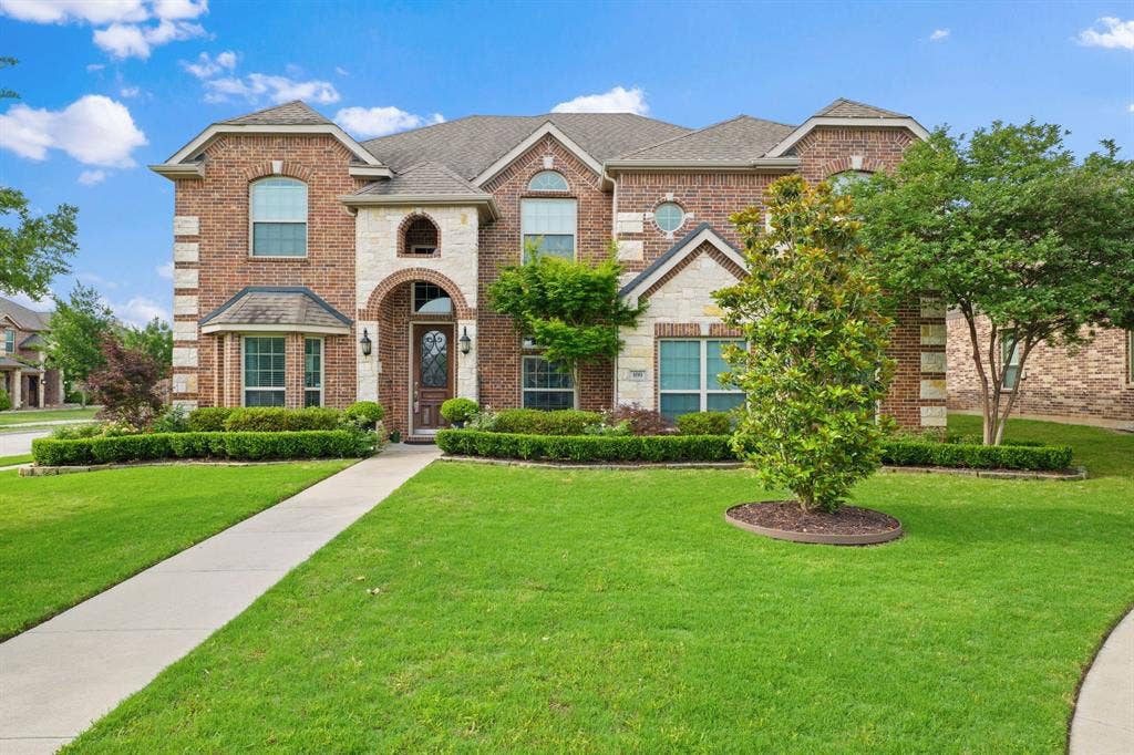 Two-story brick and stone elevation featuring multiple gables and arched window details