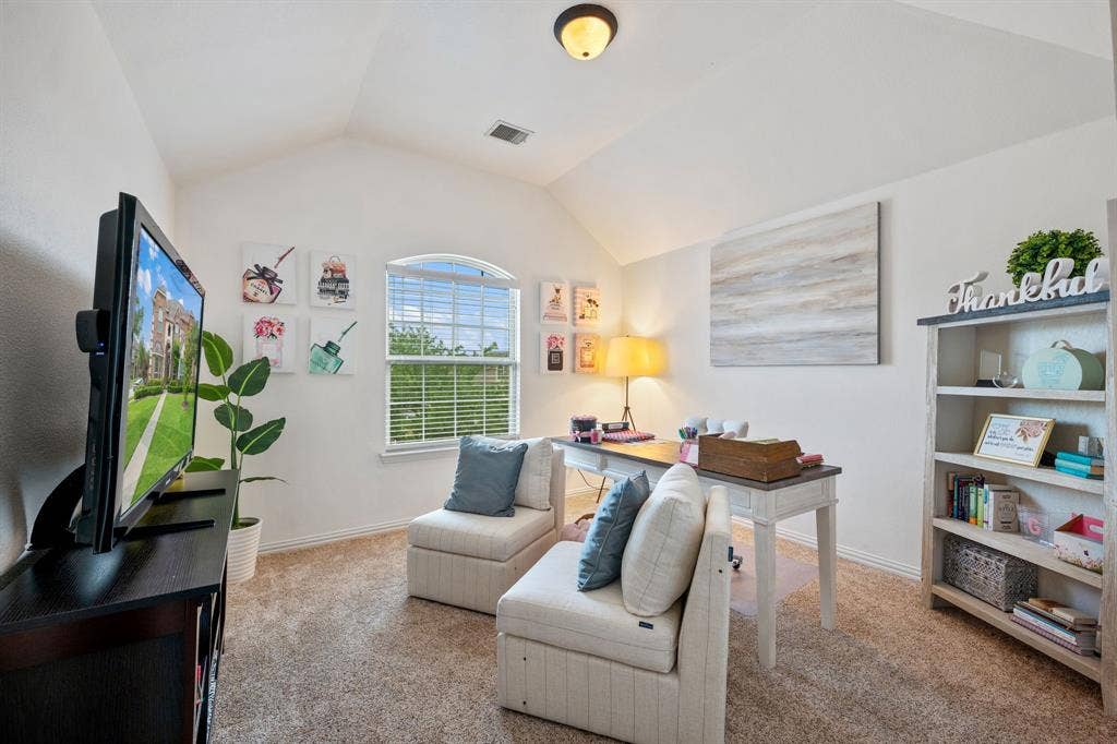 Vaulted ceiling room with an arched window, with neutral carpeted flooring