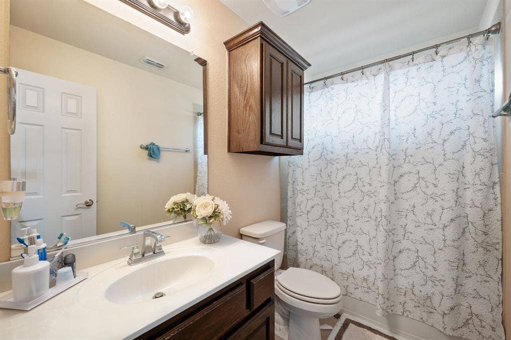 Bathroom featuring a white vanity with an integrated sink, chrome faucet, and a large wall-mounted mirror