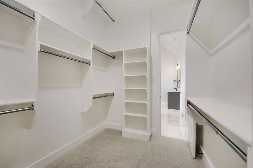 794 White Sage Road, Haslet, TX 76052 Walk-in closet featuring white built-in shelving, multiple hanging rods, and light-toned carpeting